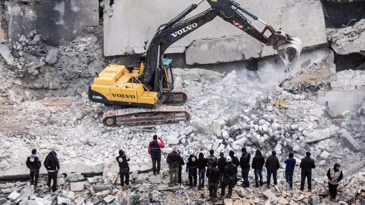 Syrian civil defense volunteers dig through the rubble of a building on March 17, 2017, in Al Jinah, Syria, after an airstrike the day before.