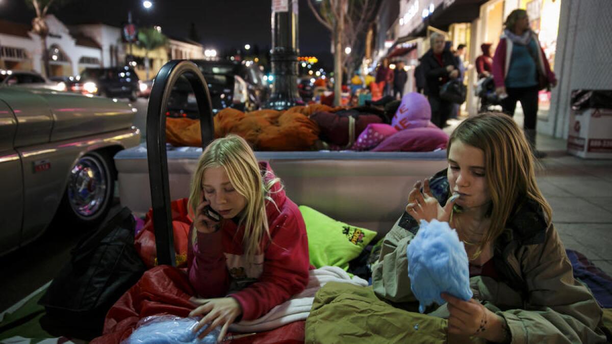 Skylar Lloyd, left, and Cam Jarman, both 12, eat cotton candy as Michelle Youngblood, center, settles in comfortably on an air mattress along Colorado Boulevard.