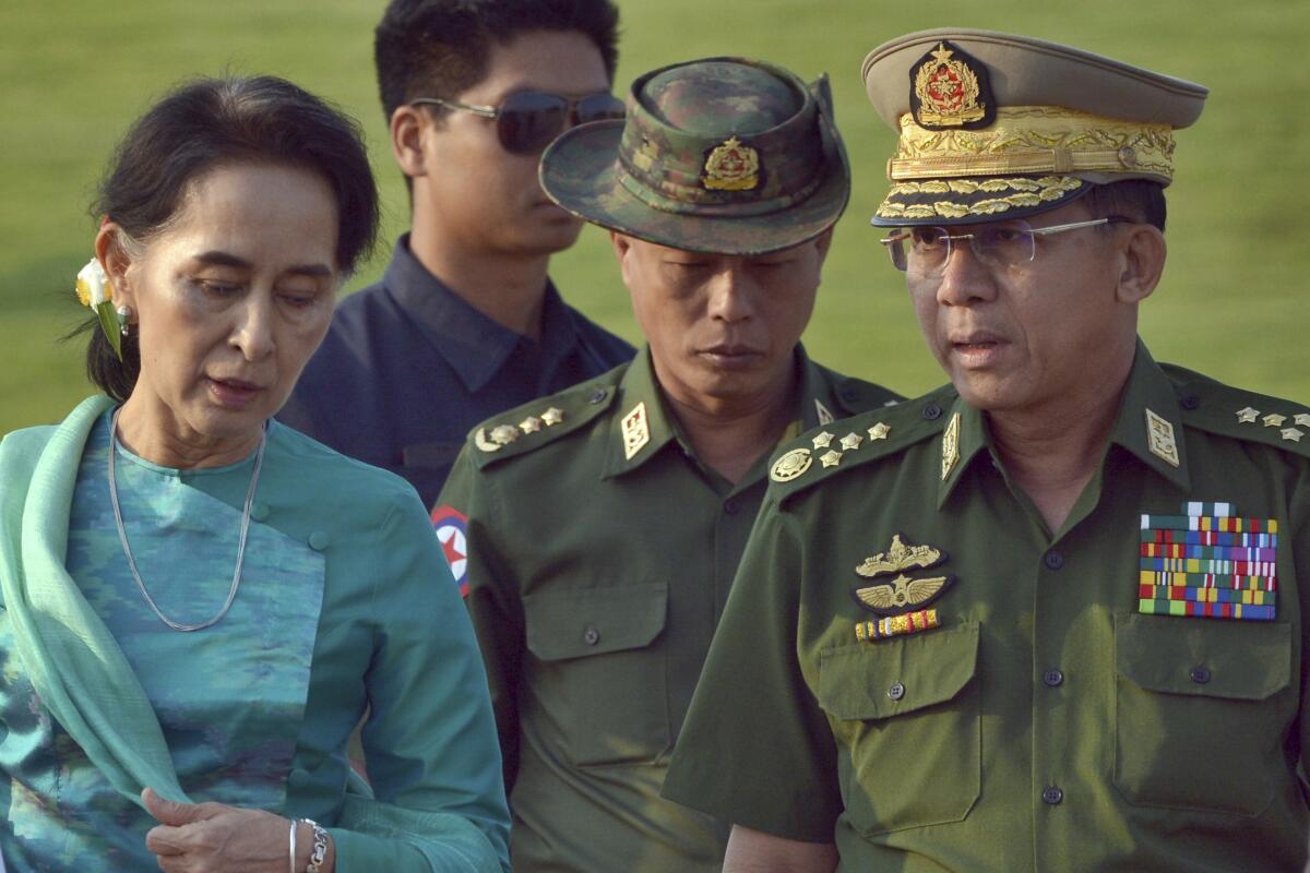Myanmar leader Aung San Suu Kyi, left, walks with Gen. Min Aung Hlaing, right