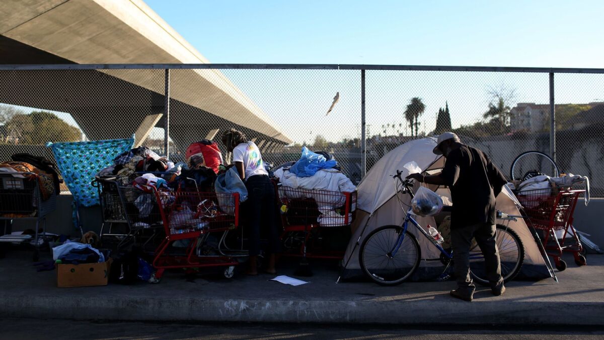 People stand outside their tents on the 42nd Street overpass over highway 110 in Los Angeles on Feb. 15, 2016.
