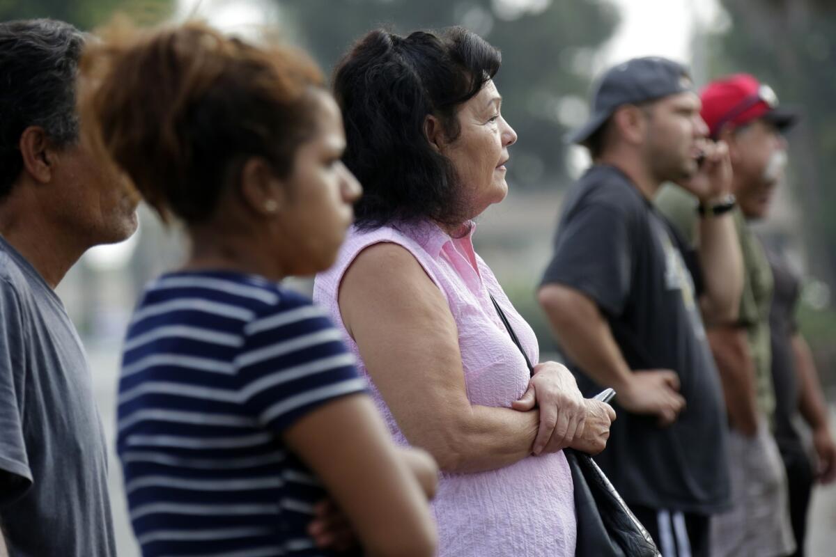 Neighbors watch as Los Angeles County sheriff's detectives investigate in Pico Rivera on Saturday after a gun battle between deputies and a wanted parolee left an innocent bystander dead.