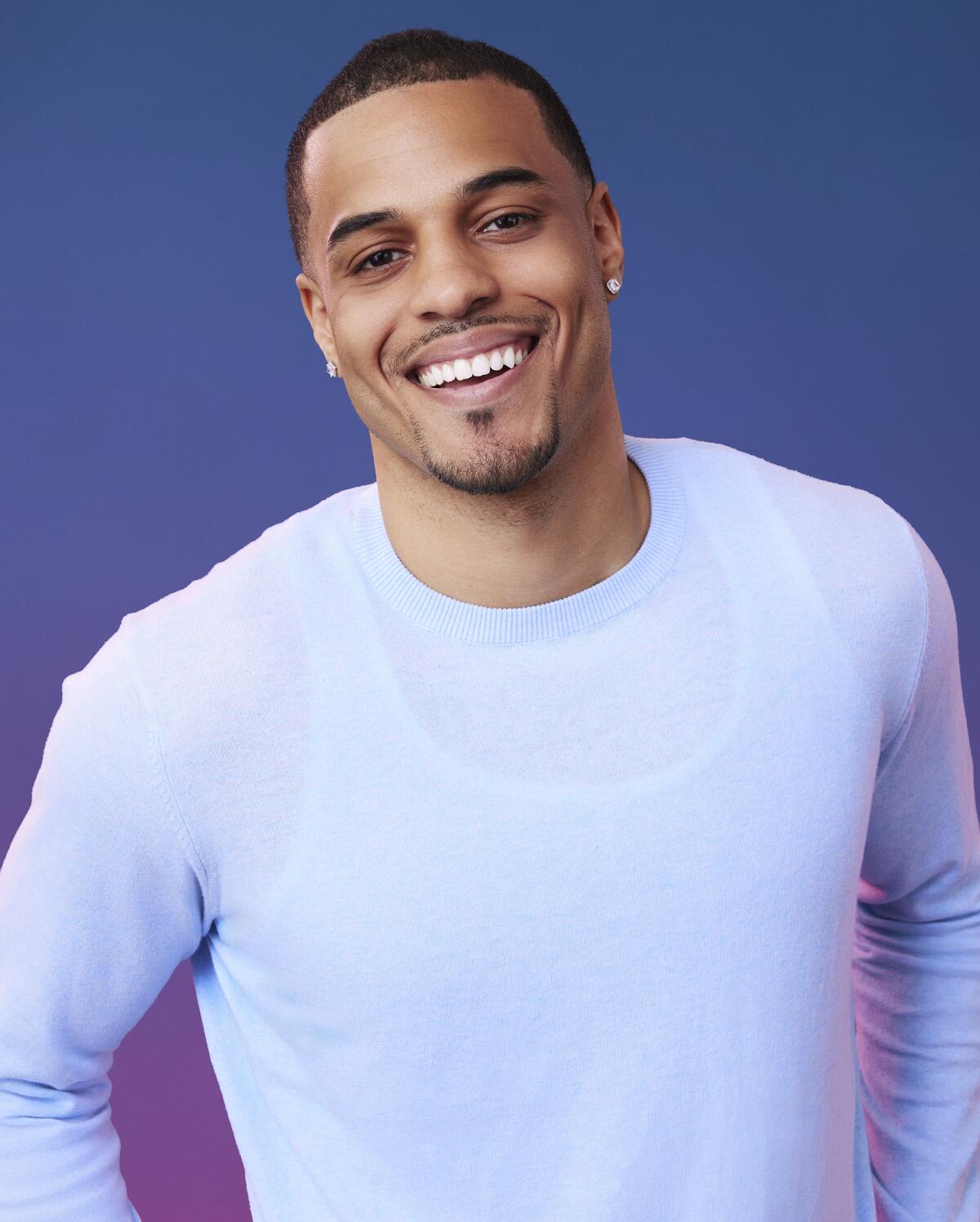 A smiling man with a goatee who is wearing a white long-sleeve shirt.