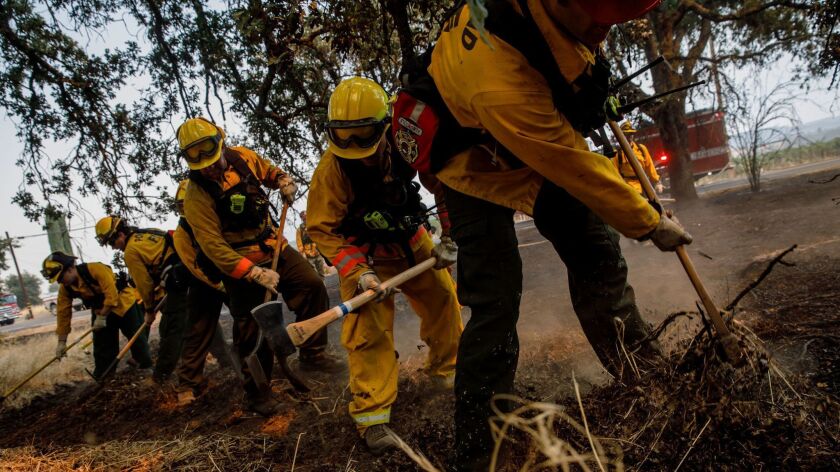 Portland firefighters do mop-up work after putting out a spot fire Tuesday on Highland Springs Road in Lakeport, Calif.