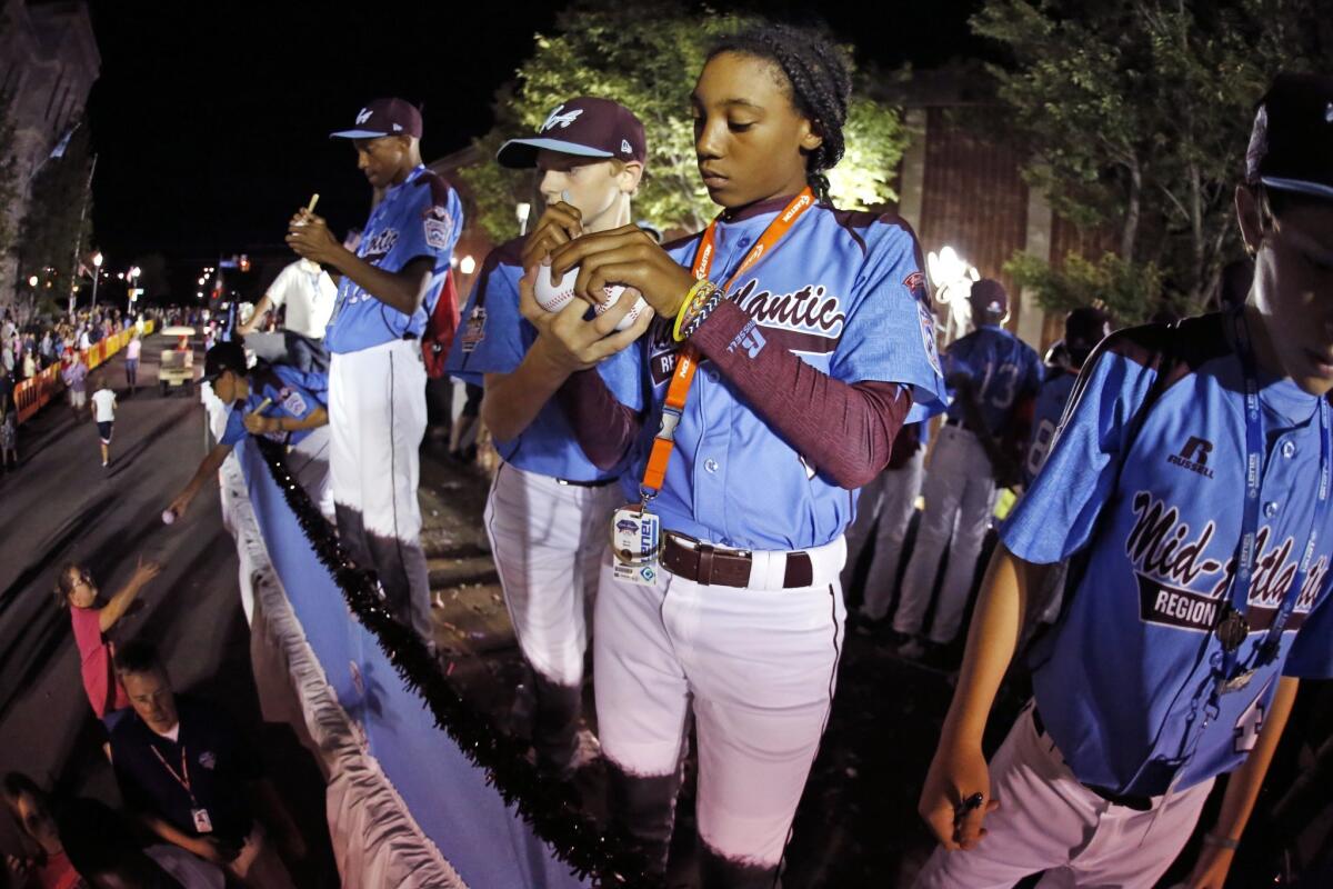 Philadelphia pitcher Mo'ne Davis signs baseballs while riding in the Little League Grand Slam Parade as it makes its way through downtown Williamsport, Pa. on Aug. 13.