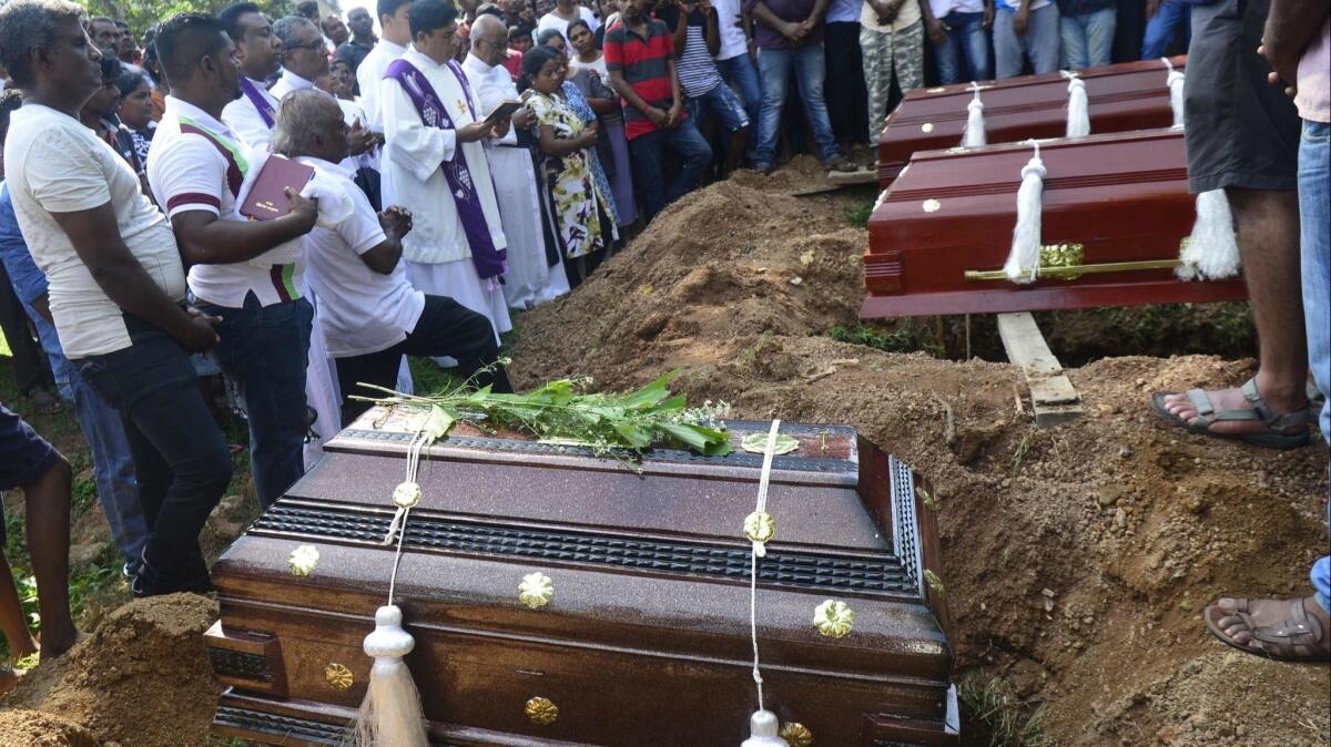 A priest administrates a burial ritual for a bomb blast victim in a cemetery in Colombo on Tuesday, two days after a series of attacks targeted churches and luxury hotels in Sri Lanka.