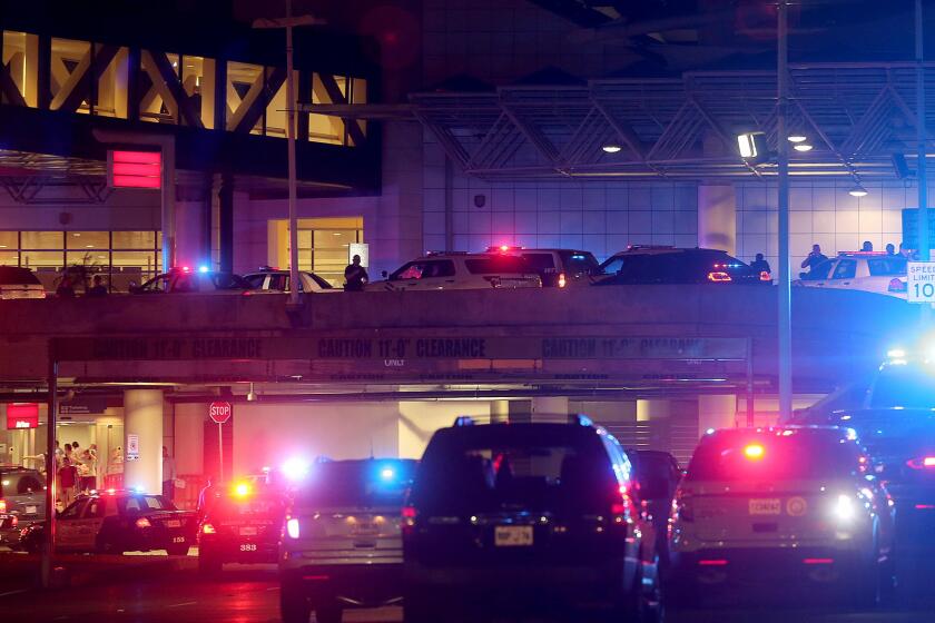 Police vehicles surround the entrance to Louis Armstrong New Orleans International Airport after a machete-wielding man was shot by a sheriff's deputy Friday night. The attacker died of his injuries Saturday.