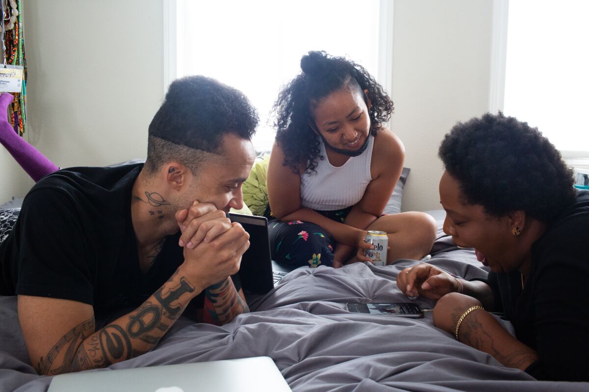 Black Lives Matter organizers Richie Reseda, Haewon Asfaw and Patrisse Cullors lie on a bed and laugh at Twitter