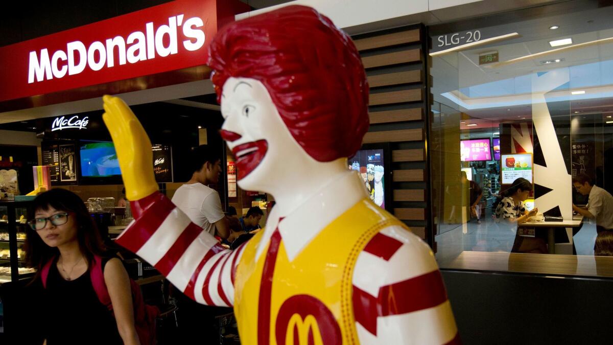 A customer walks past a statue of Ronald McDonald outside a McDonald's restaurant in Beijing in 2014.