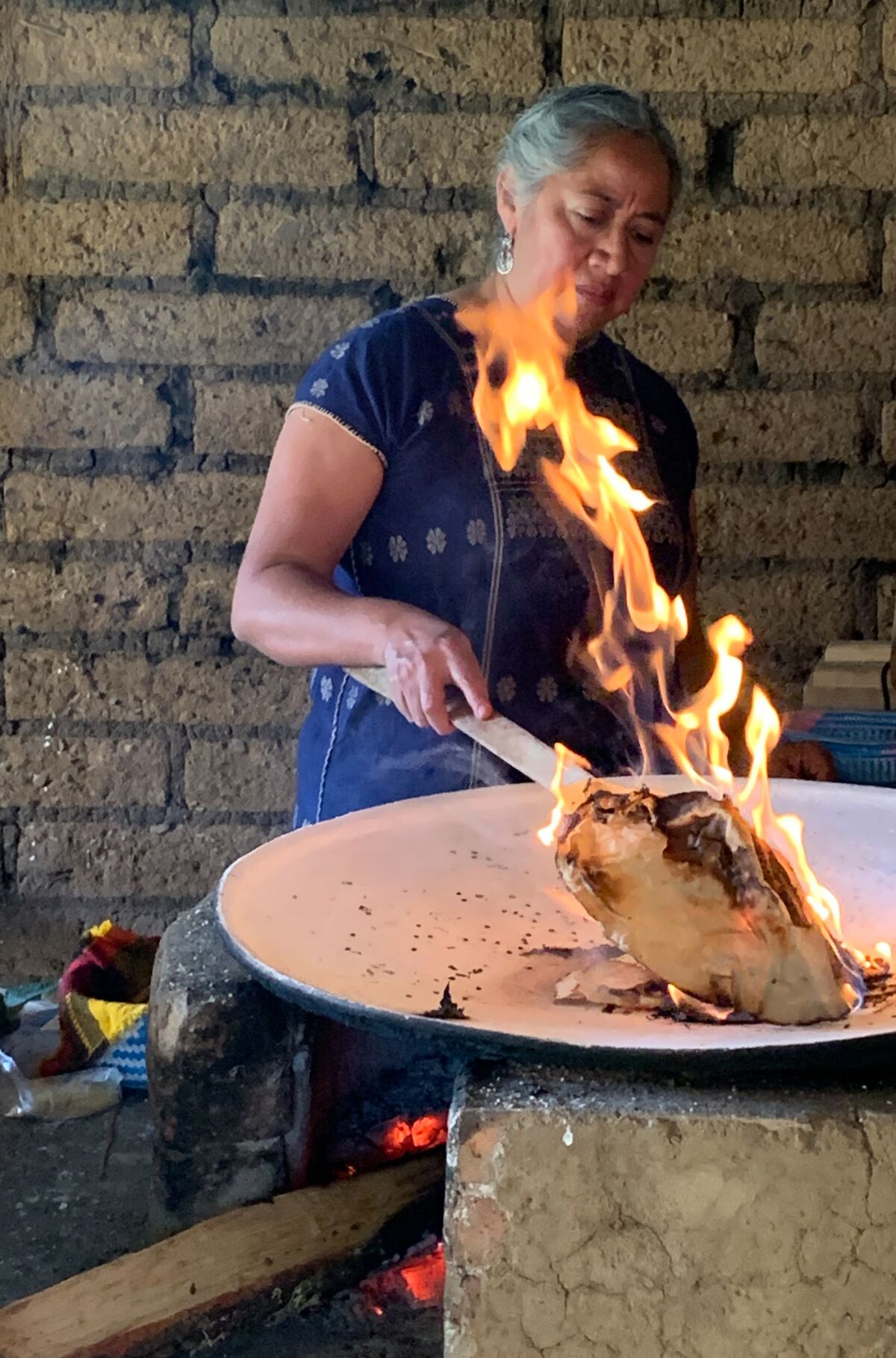 A woman roasts food in a comal.
