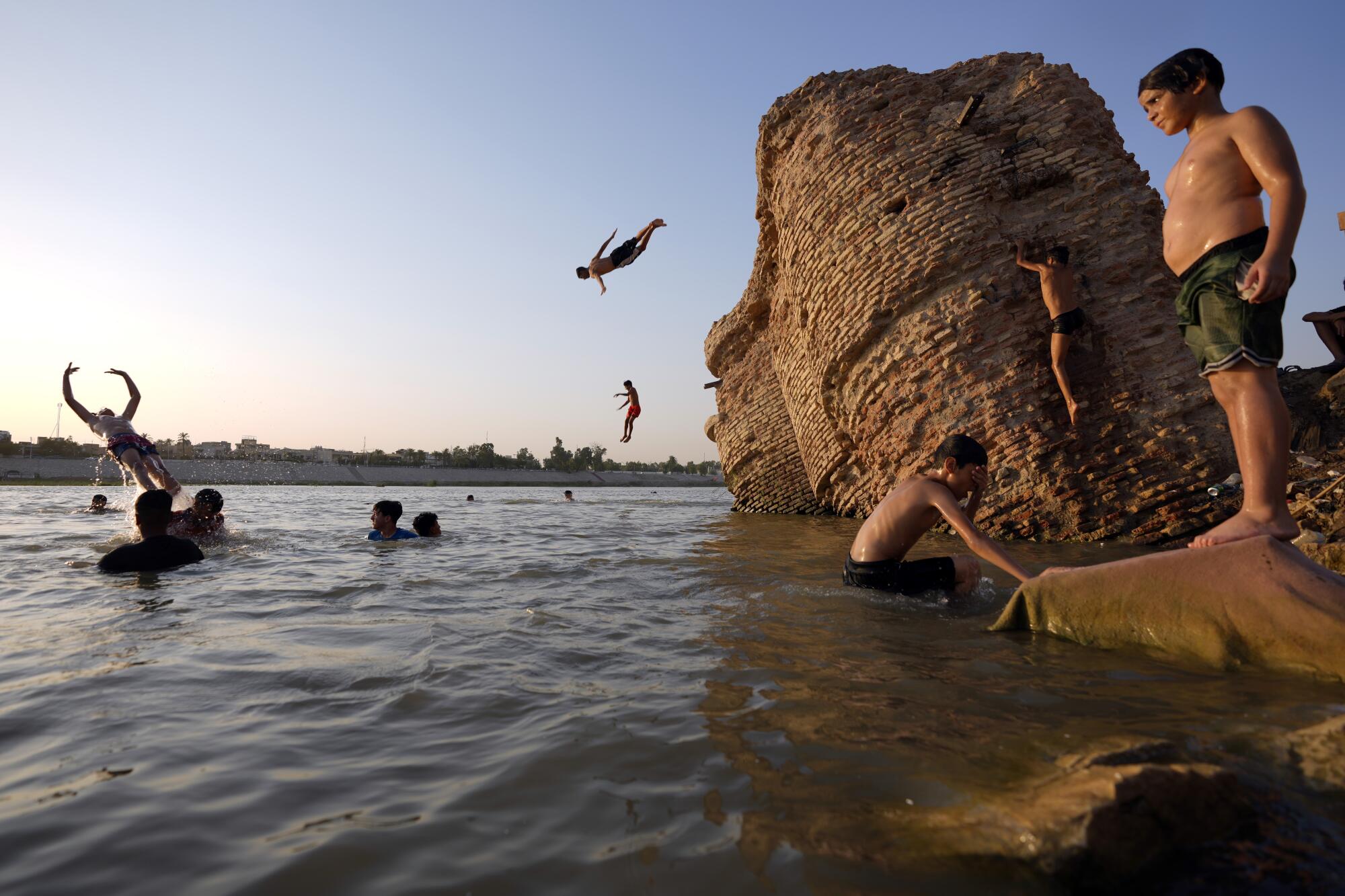 People jump into a river where people are swimming