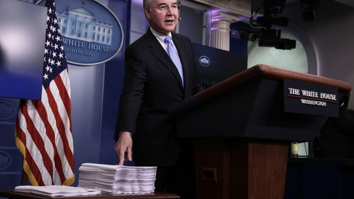 U.S. Secretary of Health and Human Services Tom Price compares a copy of the new House Republican healthcare bill, left, and the Affordable Care Act, right, on a table in the White House.