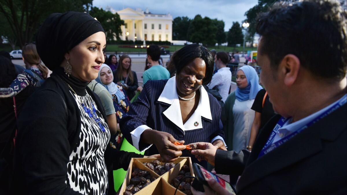 A woman offers dates, a traditional way to break the day's fast during Ramadan, on June 6 in Washington. Inside the White House, President Trump was hosting an iftar, but didn't invite American Muslims.