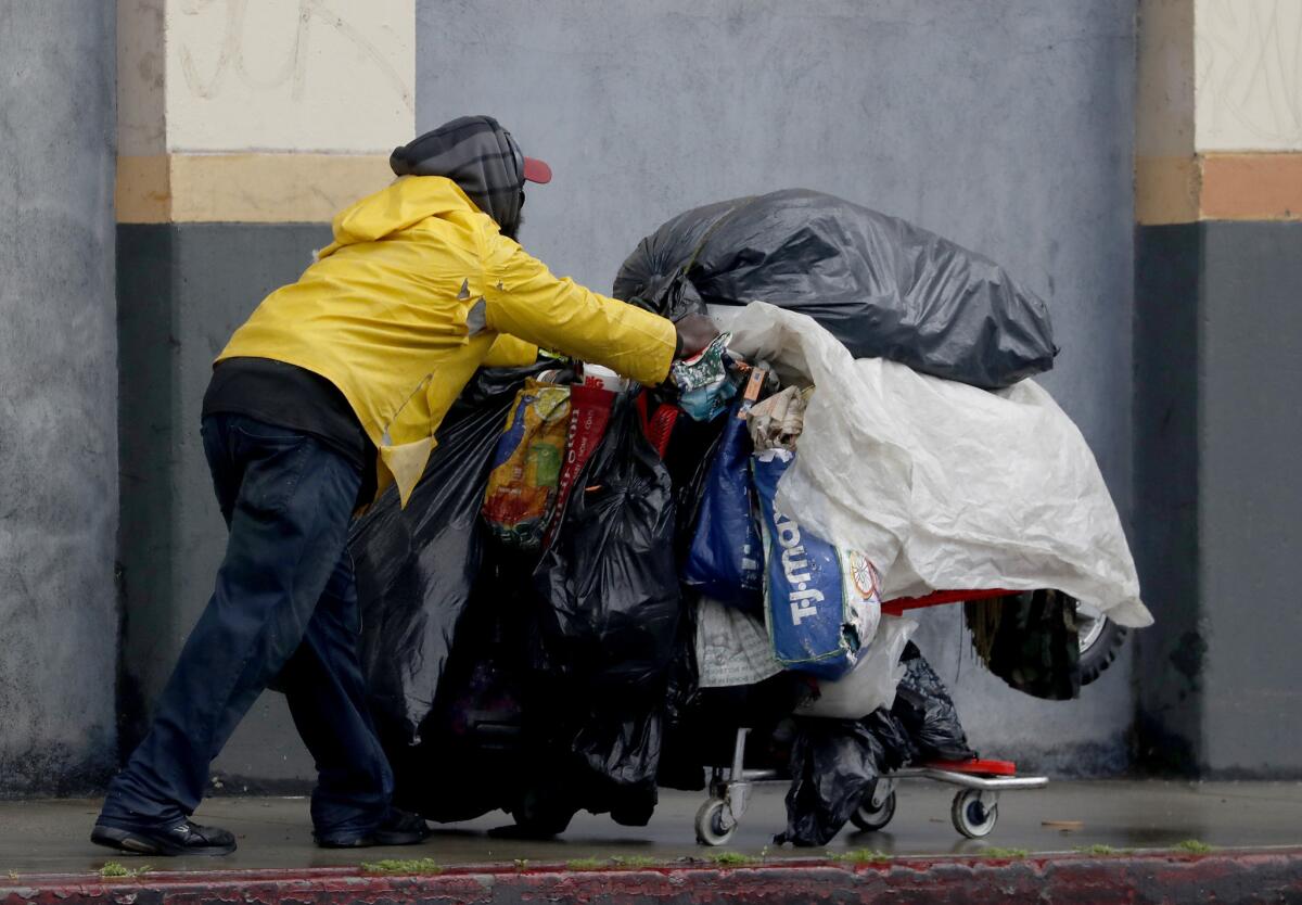 A homeless man pushes a shopping cart filled with his belongings down Seventh Street in downtown Los Angeles on Wednesday.