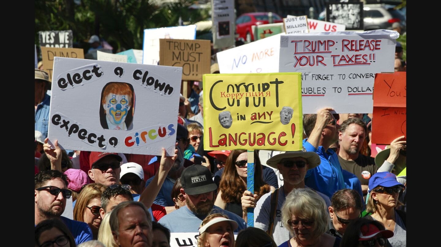 Anti-Trump protesters hold signs as they gather at the San Diego County Administration Center.