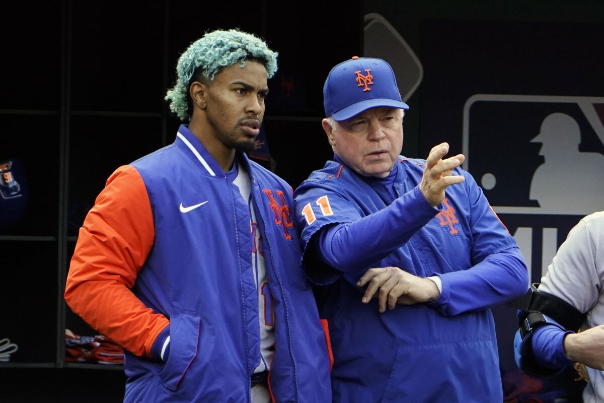 New York Mets' Francisco Lindor, left, listens as manager Buck Showalter (11) talks during the fourth inning of a baseball game against the Washington Nationals at Nationals Park, Sunday, April 10, 2022, in Washington. (AP Photo/Alex Brandon)