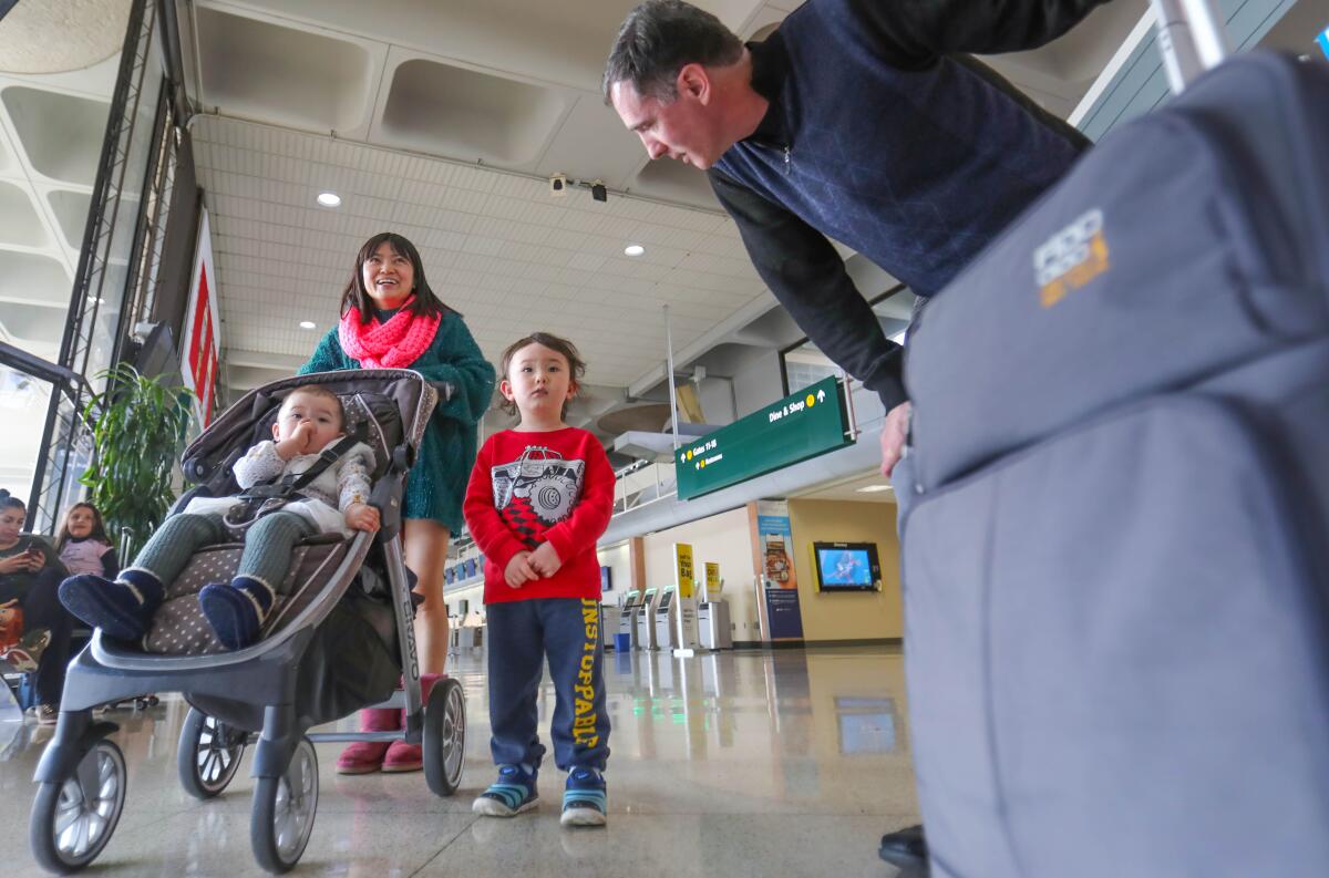 Mia Burnett, 1, in the stroller, her mom, Yanjun Wei, of Serra Mesa, and brother, Rowan Burnett, 3, all coronavirus evacuees from China, leave San Diego International Airport with with their dad, Ken Burnett, Yanjun Wei's husband, who was not in China, but traveled home with them from Sacramento, February 18, 2020, after they completed the 14-day quarantine at Travis Air Force Base.