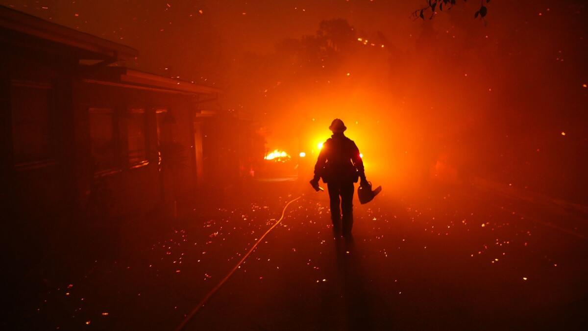 A firefighter walks toward his engine after trying to prevent the Woolsey fire from overtaking structures in Malibu.