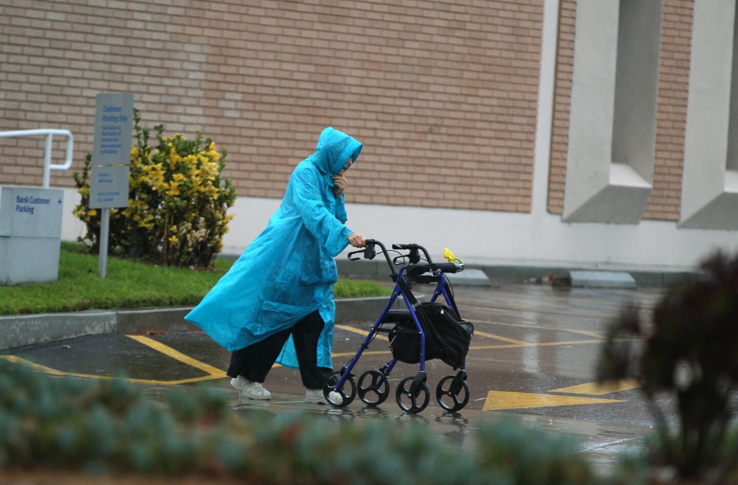 An elderly woman navigates a wet parking lot in Fountain Valley as storms were expected to barrel into Southern California in earnest Tuesday morning.