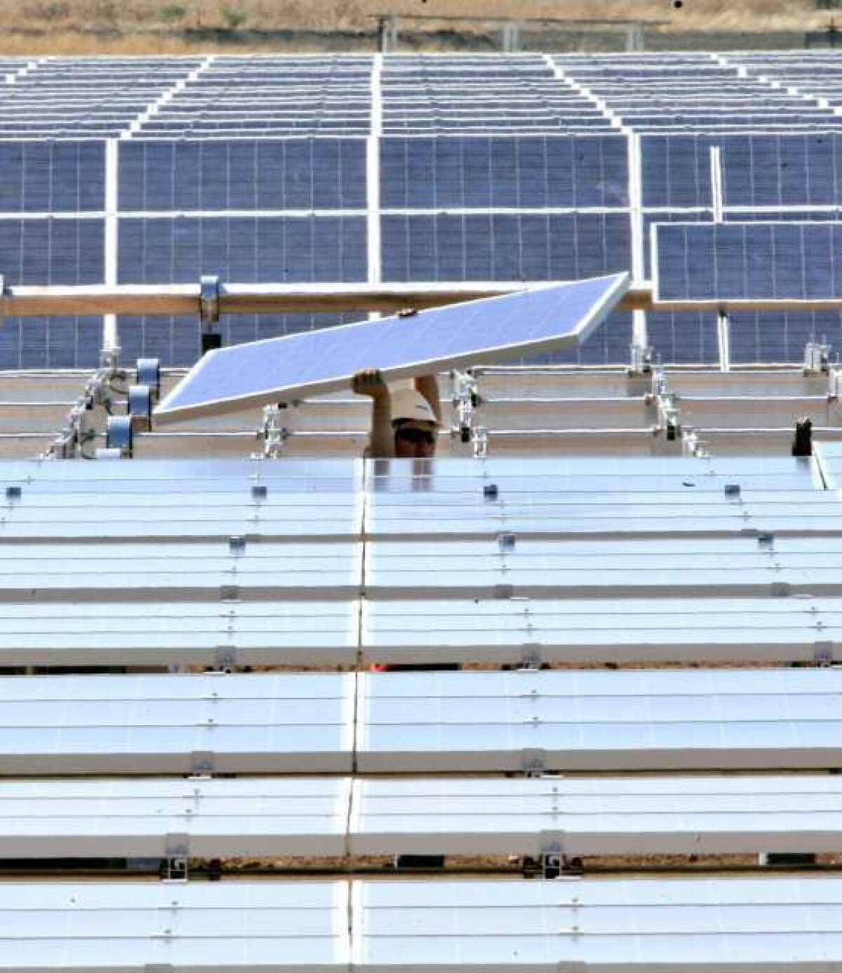 A solar energy panel is carried to be placed in a solar energy field under construction for the Sacramento Municipal Utility District.