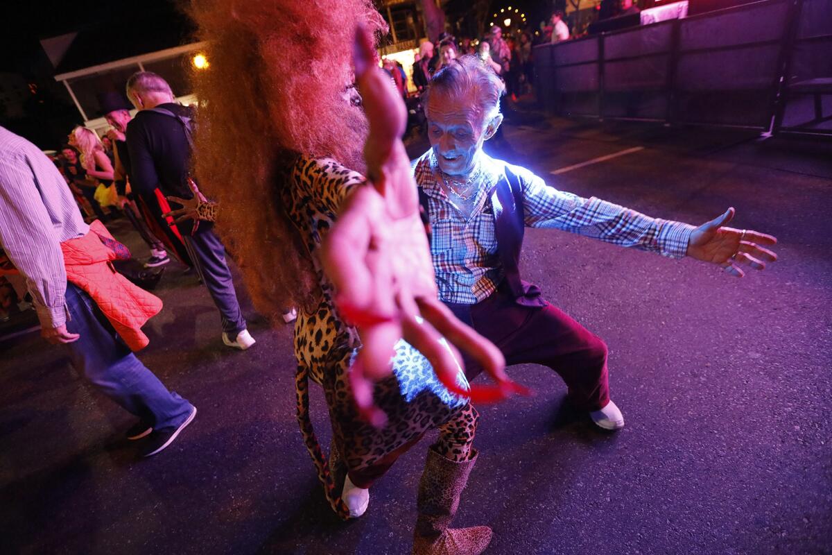 Dolly Boyd, center, dances with Abbas Hashei, 74, right, while joining the thousands of costumed revelers at the annual Halloween Carnaval.