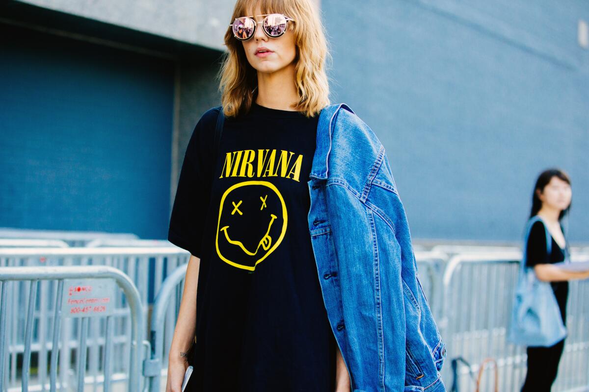 A woman wears a T-shirt with Nirvana's smiley-face logo on it