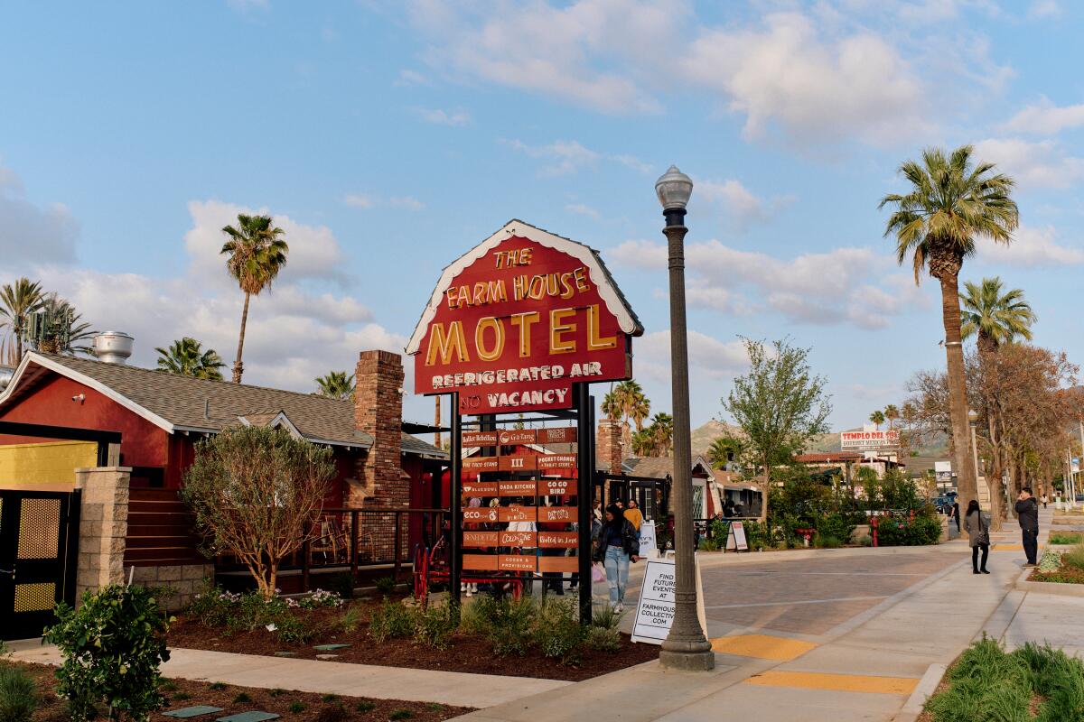 A photo of the main sign for the Farm House Motel that looks like the top of a farm house and advertises "refrigerated air."