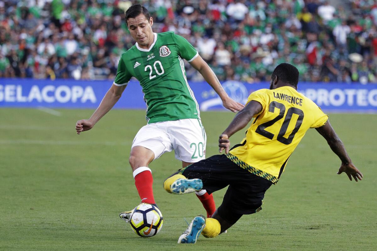 Mexico's Jesus Duenas, left, passes the ball as he is pressured by Jamaica's Kemar Lawrence, right, during the second half of a CONCACAF Gold Cup semifinal soccer match in Pasadena, Calif., Sunday, July 23, 2017. (AP Photo/Jae Hong)