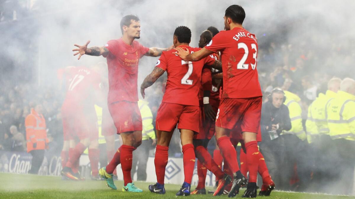 In a haze from a lit flare, Sadio Mane and Liverpool teammates celebrate their first goal in a match against Everton at Goodison Park on Dec. 19.