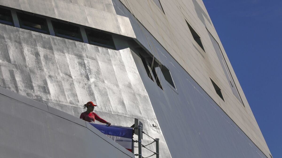 Lucina Reed attaches red white and blue bunting on the rails of the deck on the future USS Michael Monsoor, in preparation for Saturday's commissioning.