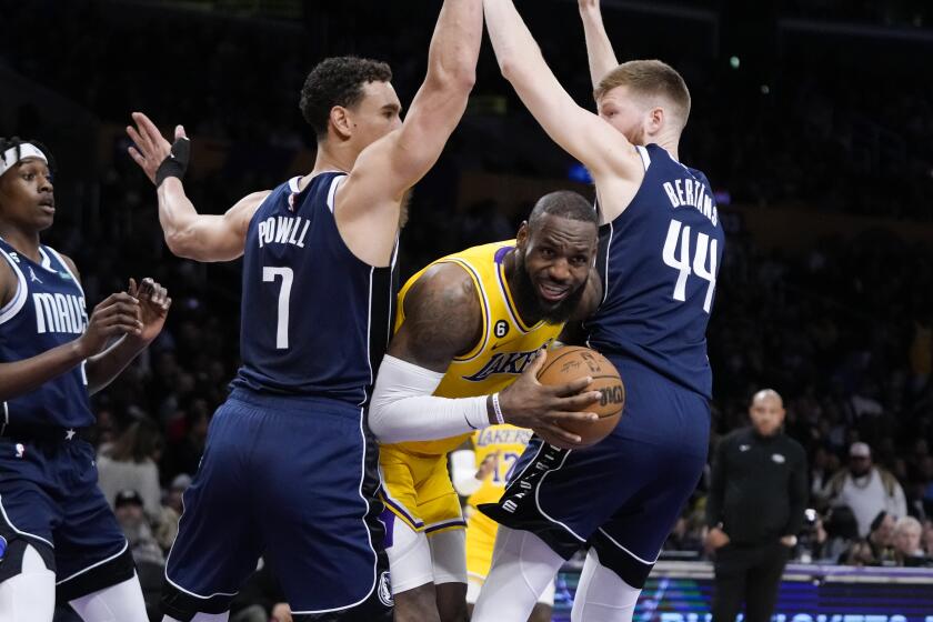 Los Angeles Lakers' LeBron James (6) is defended by Dallas Mavericks' Dwight Powell (7) and Davis Bertans (44) during the first half of an NBA basketball game Thursday, Jan. 12, 2023, in Los Angeles. (AP Photo/Jae C. Hong)