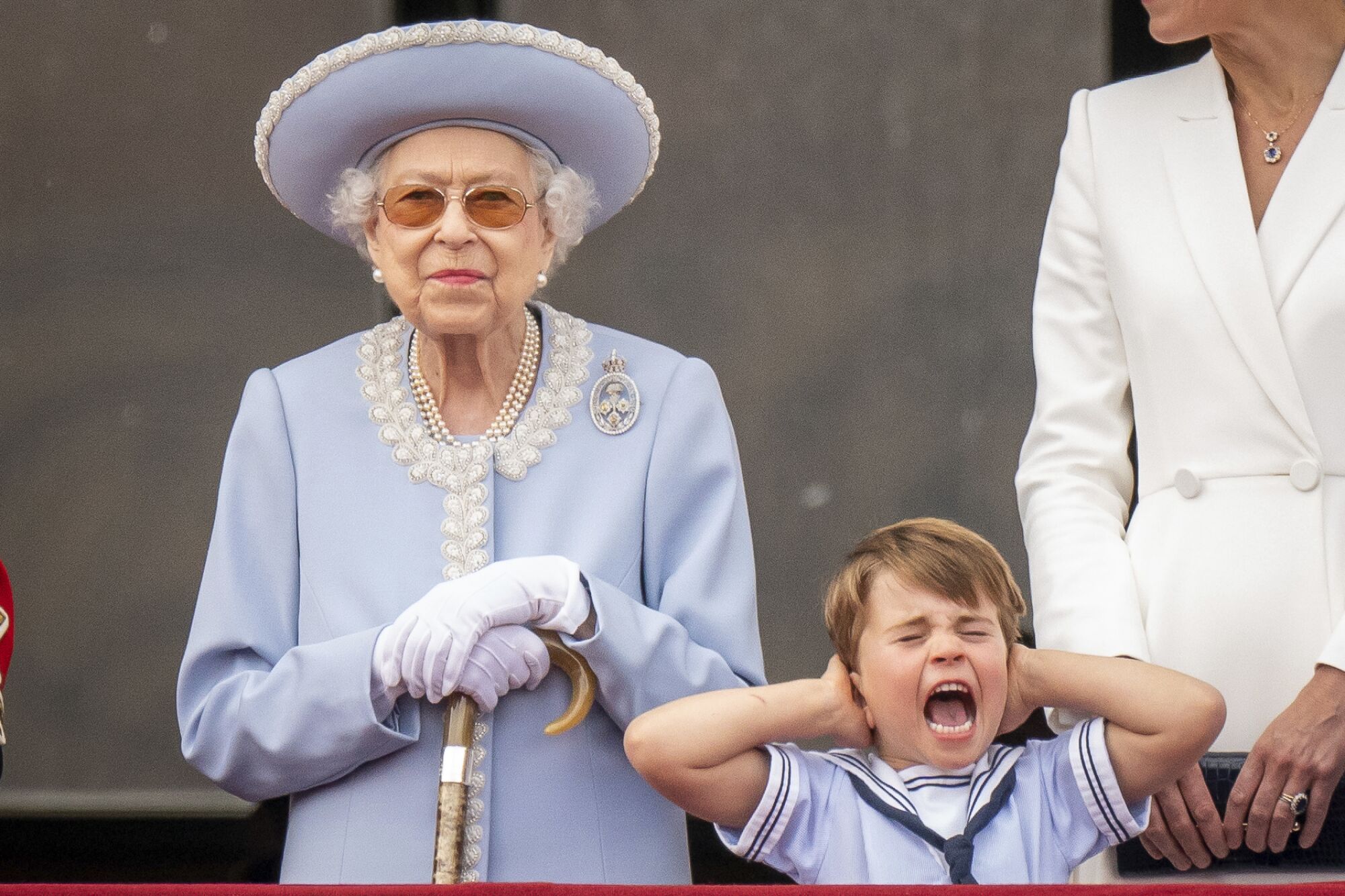 Queen Elizabeth II stands as Prince Louis covers his ears on the balcony of Buckingham Palace.
