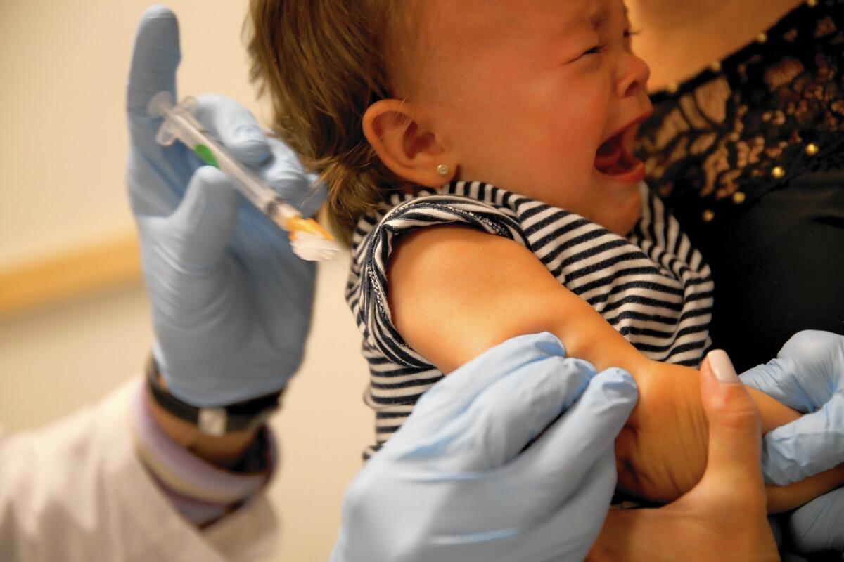 A pediatrician administers a measles vaccination to a young child. In California, a measles outbreak has sickened dozens of people.
