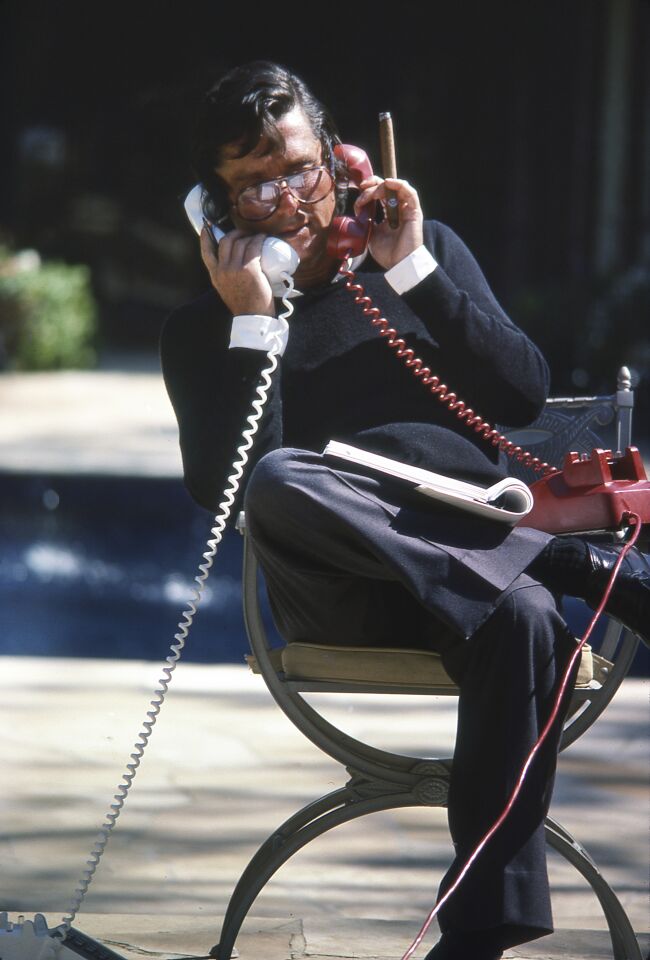Robert Evans sits poolside with two telephones in the garden of his Beverly Hills home around 1978.