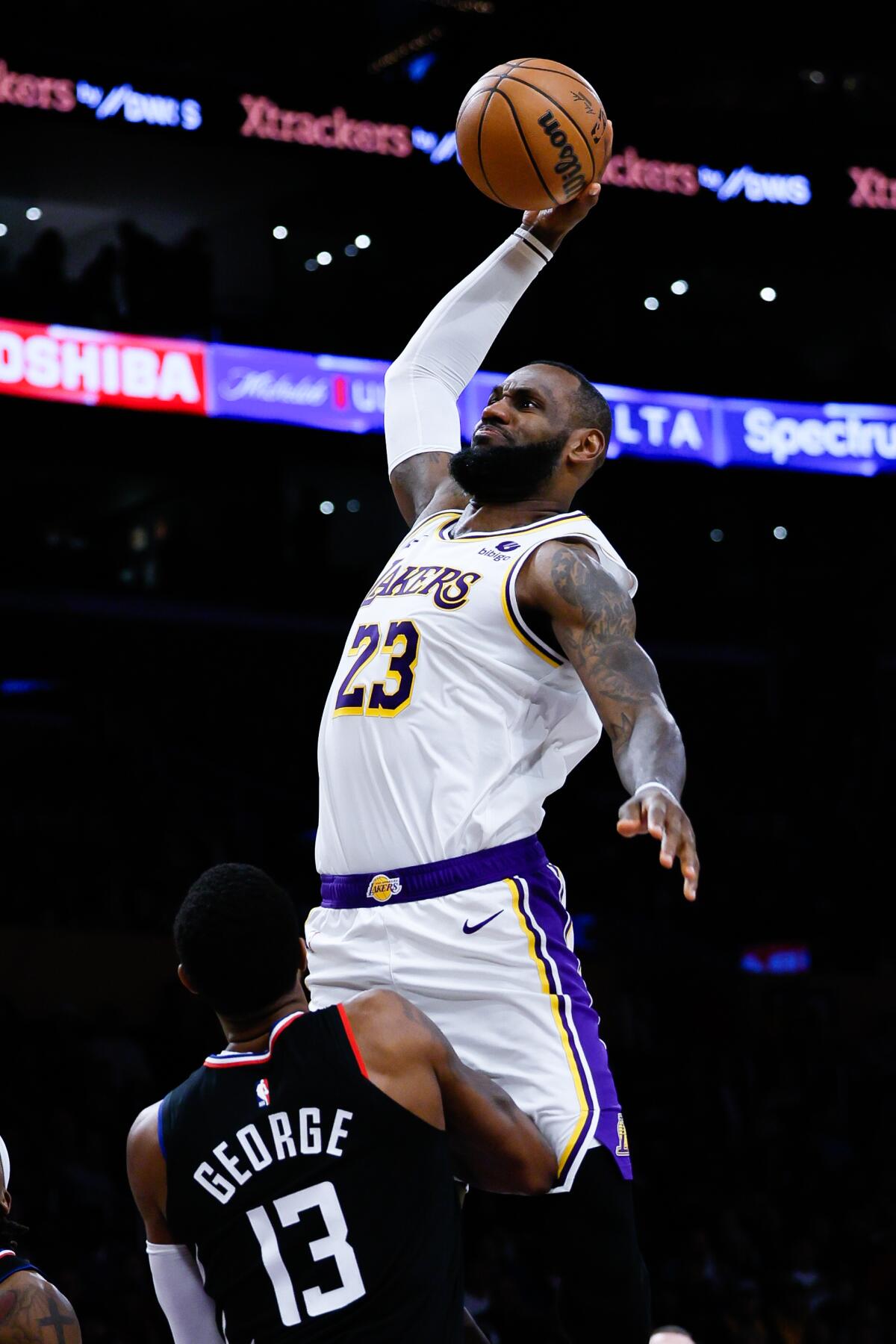 Lakers star LeBron James dunks in front of Clippers forward Paul George during the second half Sunday at Crypto.com Arena.