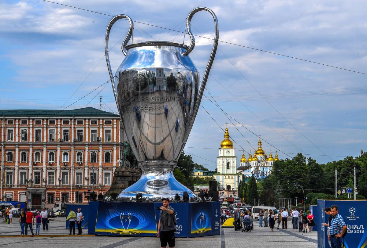 Aficionados posan ante una réplica gigante del trofeo de la Liga de Campeones en Kiev, Ucrania, hoy, 24 de mayo de 2018. El Real Madrid se enfrentará al Liverpool en la final de la Liga de Campeones el próximo 26 de mayo en la capital ucraniana.