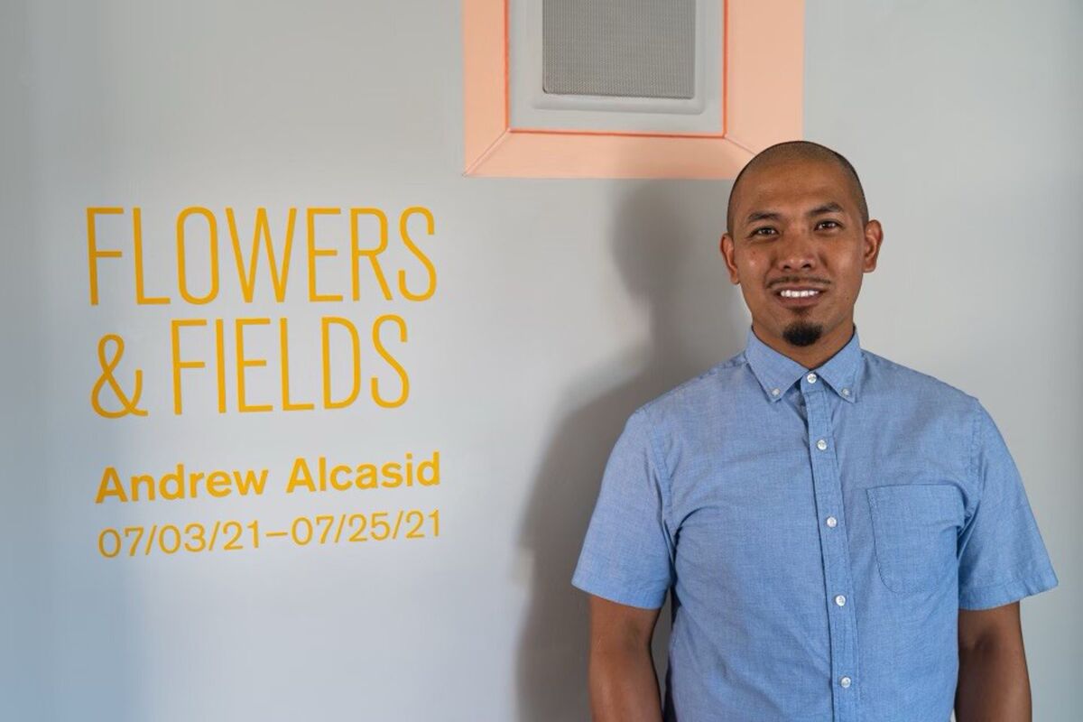 San Diego artist Andrew Alcasid poses in front of his latest exhibition, "Flowers & Fields"