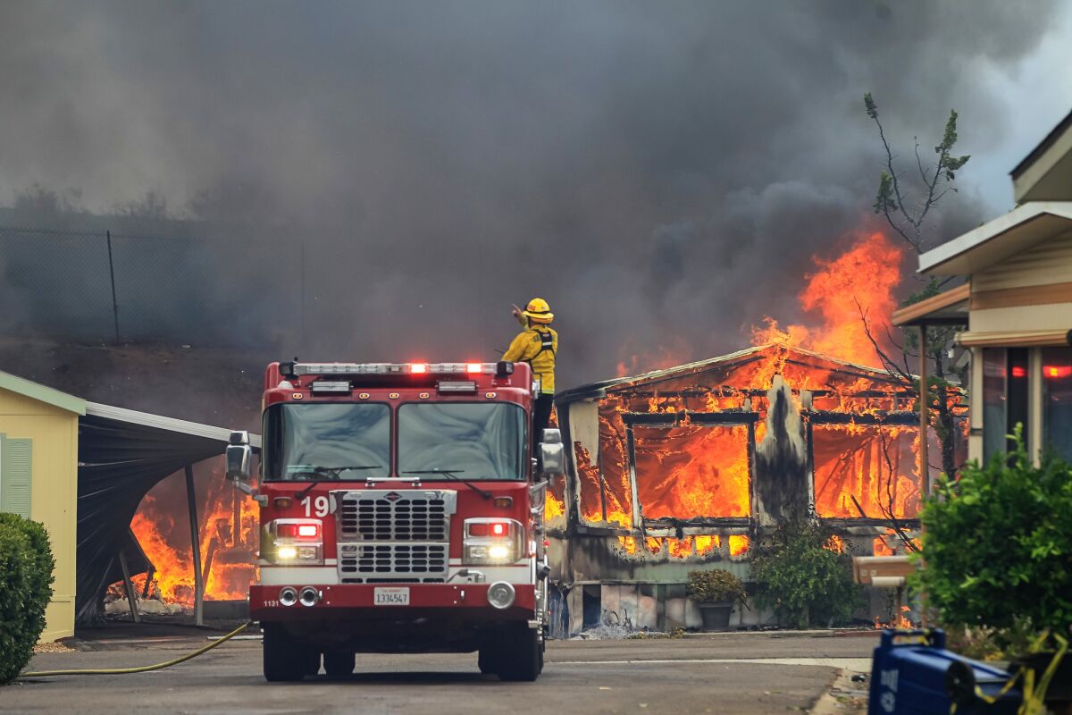 Firefighters wait for water as they battle flames at the Alpine Oaks Estates mobile home park on Friday.
