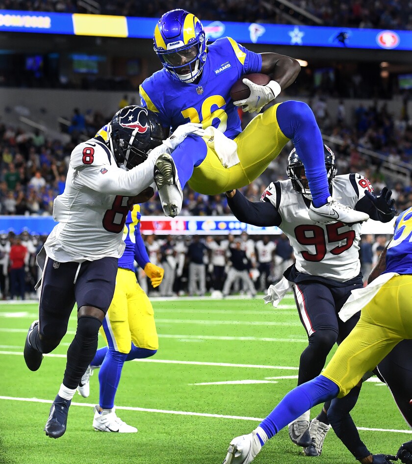 Rams quarterback Bryce Perkins leaps over Texans' Terrance Brooks, left, and Derek Rivers in the third quarter.