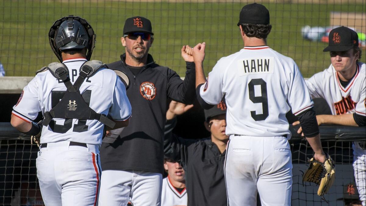 Coach Benji Medure, shown congratulating Josh Hahn (9) on March 1, leads the Huntington Beach High baseball team into the CIF Southern Section Division 1 playoffs.