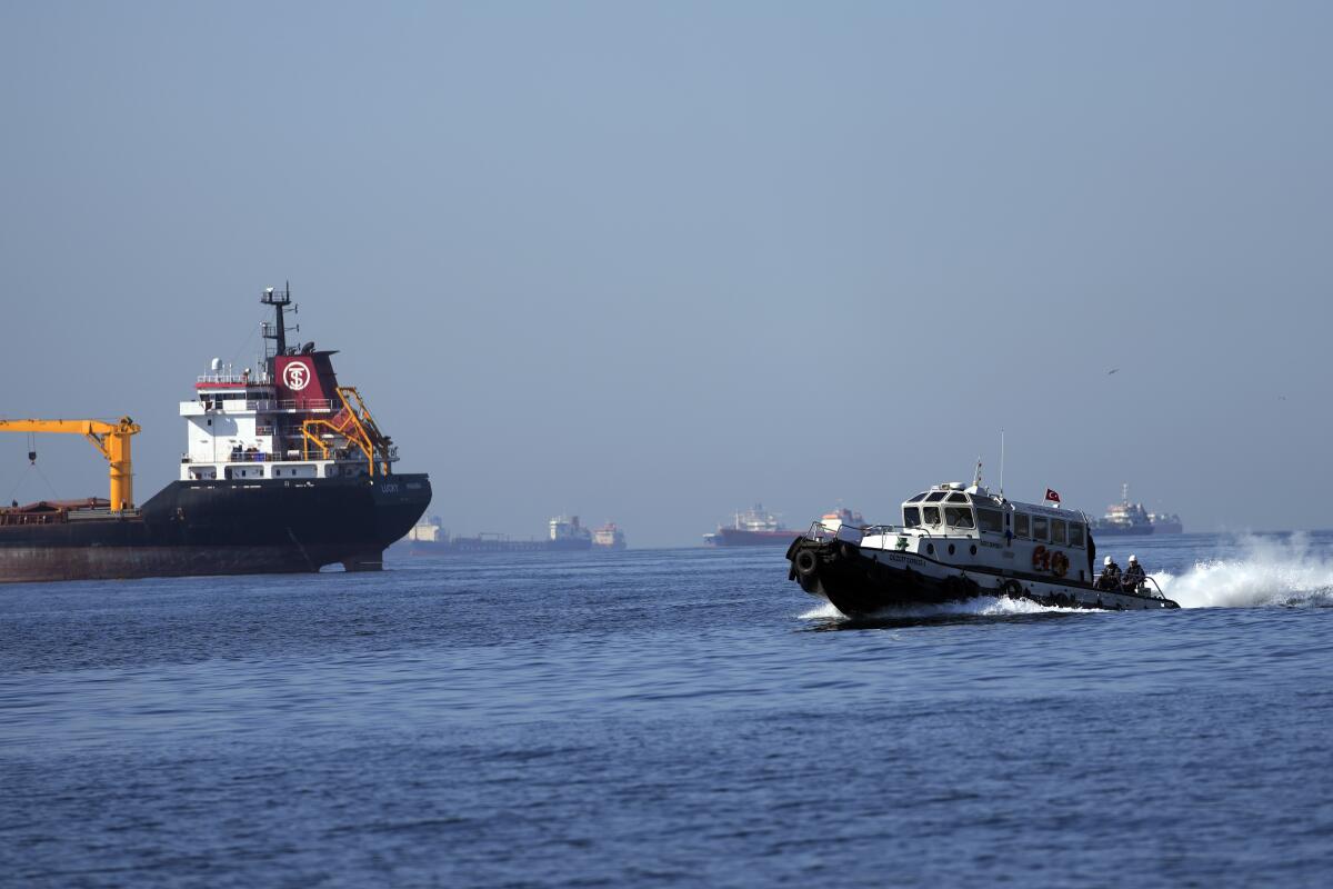 A boat with officials heads through the sea to inspect cargo ships.