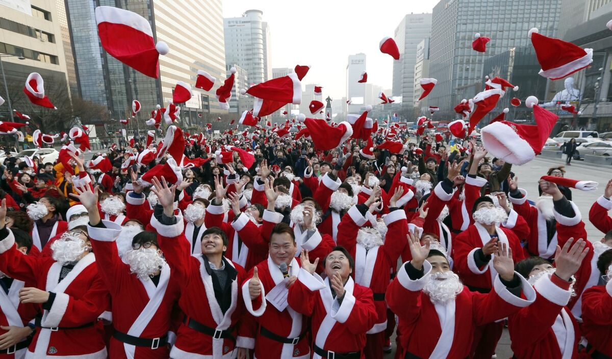 Volunteer Santa Clauses throw their hats in the air during a Christmas charity event in Seoul in 2015.