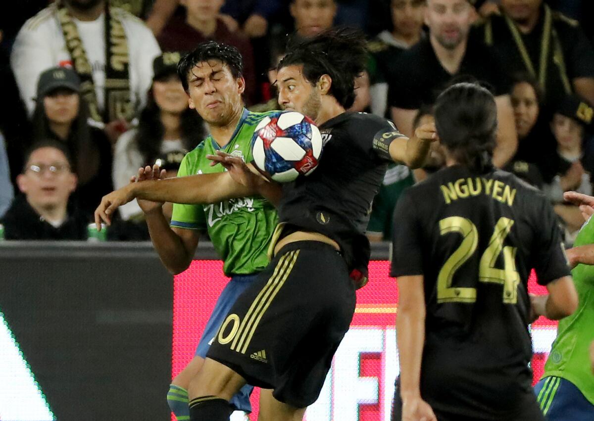 LAFC's Carlos Vela, right, battles Seattle's Xavier Arreaga for control of the ball during the first half.