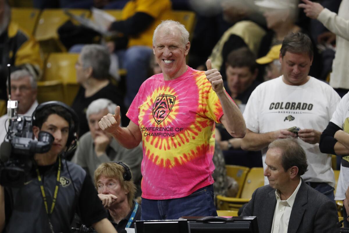 Television announcer and retired NBA star Bill Walton, center, smiles as he takes his seat courtside.