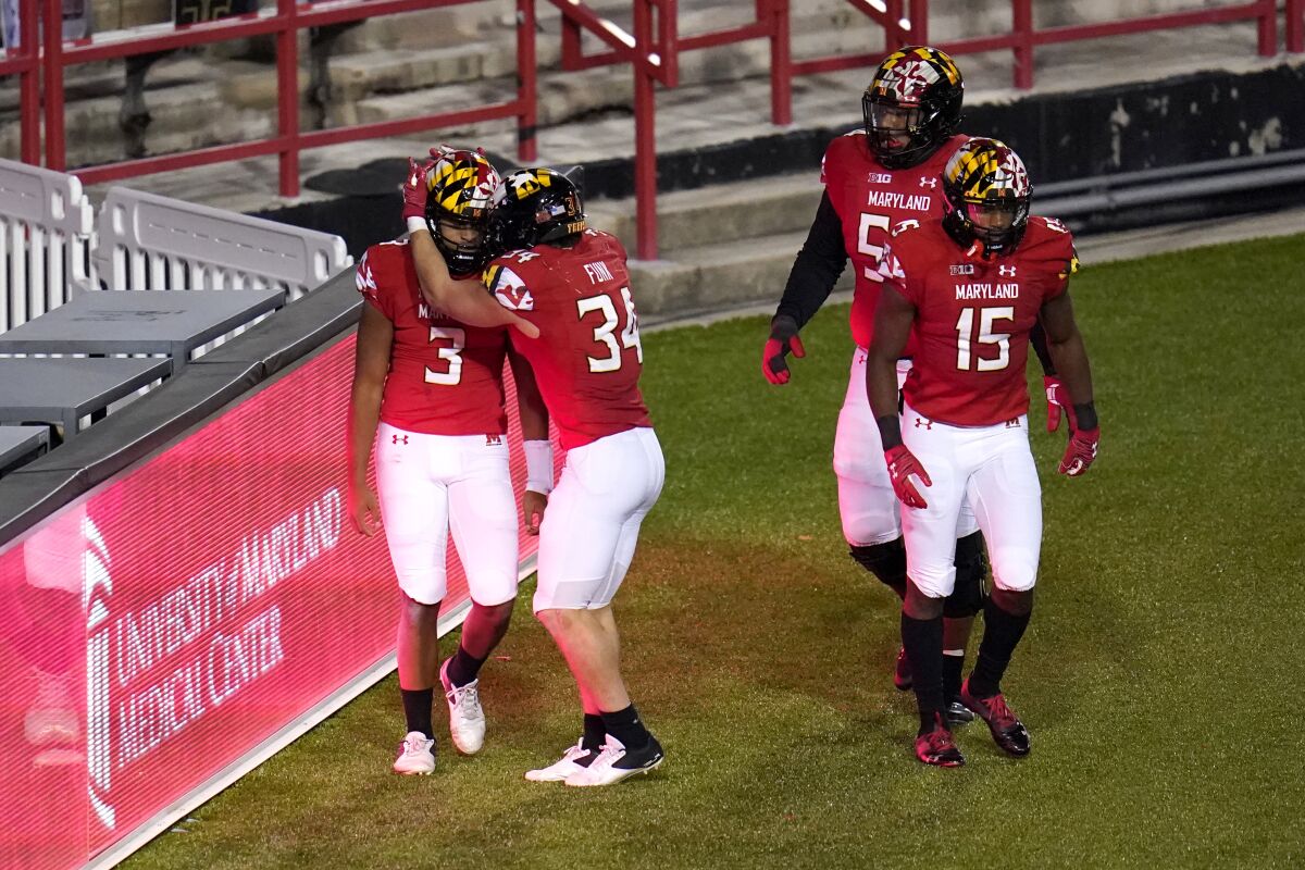 Maryland's Taulia Tagovailoa (3) is congratulated by Jake Funk (34) after scoring an overtime touchdown against Minnesota.