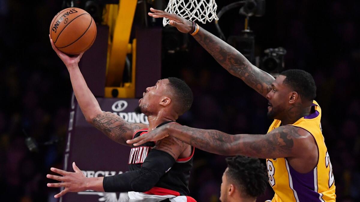 Portland guard Damian Lillard, left, shoots as Lakers center Tarik Black defends on Jan. 10.