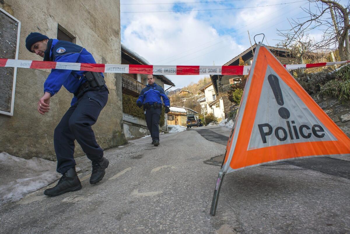 Police officers men walk in the village of Daillon, Switzerland, where three people were shot and killed.
