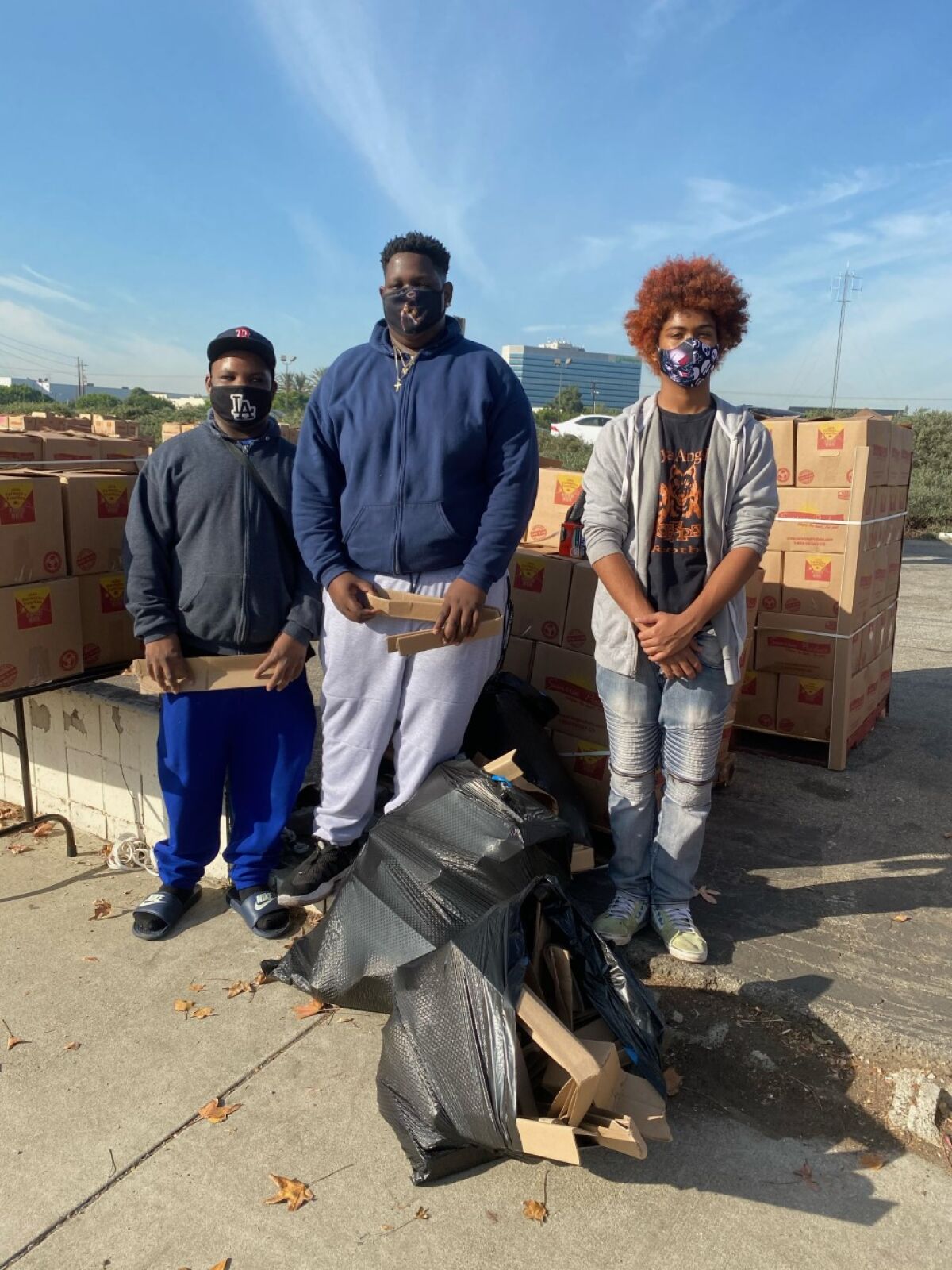 Angelou football players Malik Bradford, Michael Bradford and Semaja King help move boxes of food.