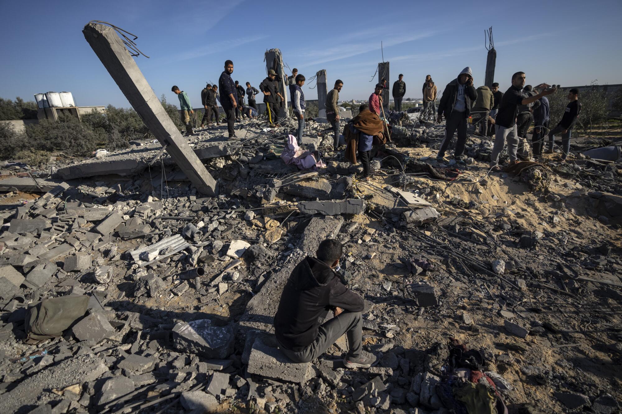 Des gens au milieu des décombres d’une maison détruite lors d’une frappe aérienne israélienne dans le sud de Gaza