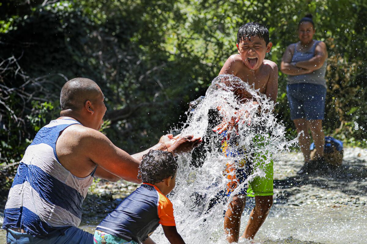 Orlando Miranda splashes with his young sons in a stream at Lytle Creek.
