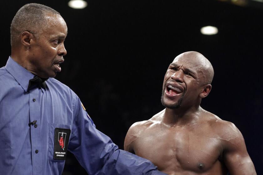 Referee Kenny Bayless holds back Floyd Mayweather Jr. after the boxer accuses Marcos Maidana of a low blow during Mayweather's victory on Sept. 13, 2013.